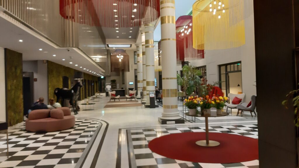 The lobby is a long corridor with a shiny stone floor. There are a number of sitting areas and low tables throughout the length of the corridor.