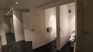 The toilets are in cubicles with full-height doors. The doors open out into the room and vary between opening left or right.